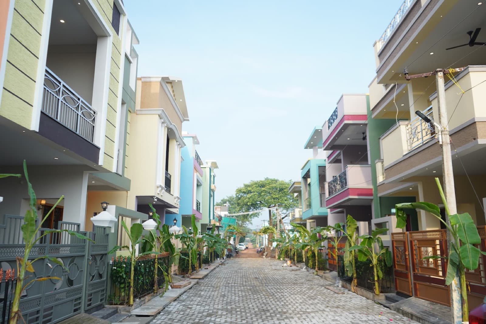 A paved lane between a row of coloured villas, with banana plants along the gates. Published on the SPR Paradise and MSS resort sites.